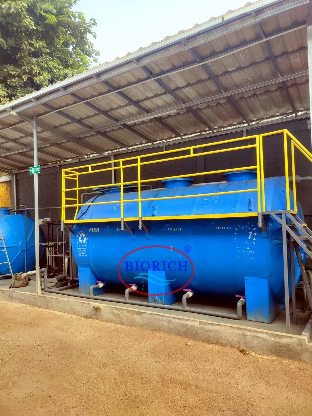 Unit IPAL BIORICH horizontal dengan platform dan tangga, terpasang di bawah kanopi di lokasi proyek